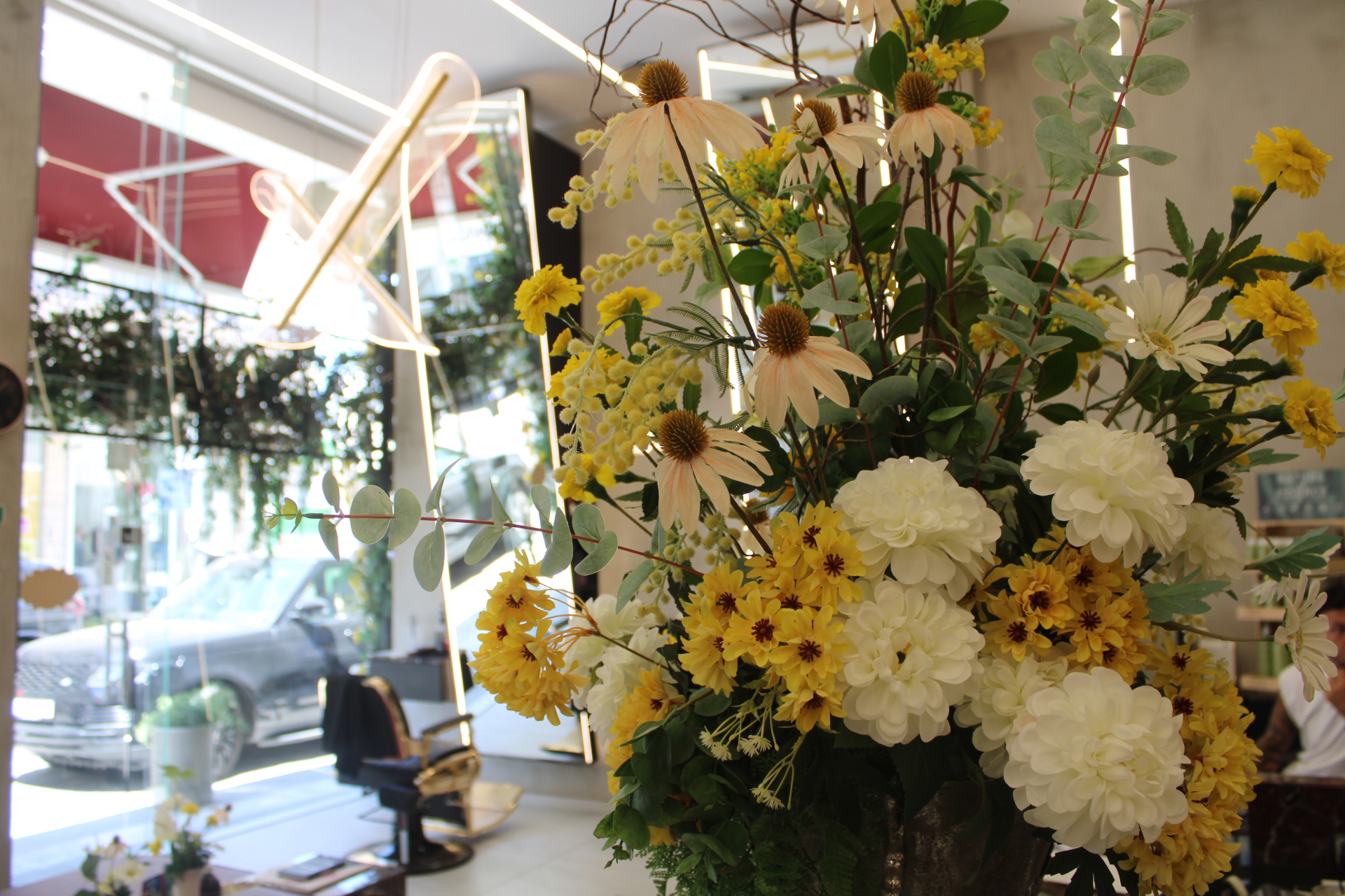 The FLO LONDON salon in Larnaca, sunlit with a full arrangement of yellow and white flowers